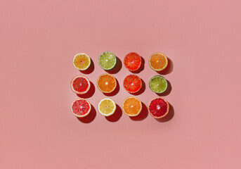Poster - Twelve citrus fruit slices arranged in rows on a pink background.