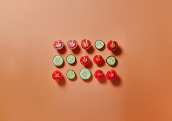 Poster - Sliced cucumbers and tomatoes arranged in rows on an orange background.
