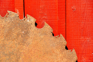 A large saw blade in front of a red barn.