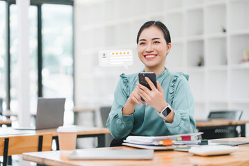 Woman in an office smiles while reading a 5-star online review on her smartphone.