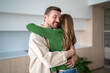© DimaBerlin - Happy loving married couple standing with embrace in apartment rejoicing moving day, fulfillment of dream about new home. Pleased man hugging woman wife feeling support, celebrating goal achievement.