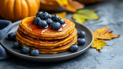 Poster - Pumpkin pancakes with maple syrup and blueberries on a plate Grey stone background Top view Copy space : Generative AI