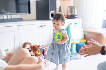 A 1 year old Taiwanese girl spending time playing happily with her parents, a man and woman in their 20s, in a room of a high rise apartment in Taichung City, Taiwan.