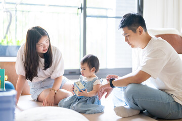 A 1 year old Taiwanese girl spending time playing happily with her parents, a man and woman in their 20s, in a room of a high rise apartment in Taichung City, Taiwan.