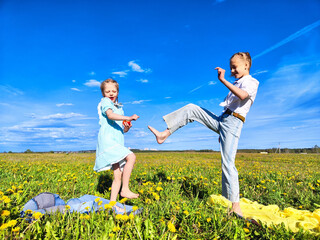 Two children joyfully playing in a dandelion-filled field on a sunny afternoon