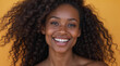 © Daniel L - A beautiful African American model with a broad smile is posing in front of a yellow studio backdrop. She has long wavy hair, promoting hair care. She has a flawless complexion.