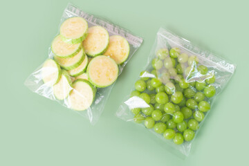 Vegetables in cellophane bags on green background close-up top view.