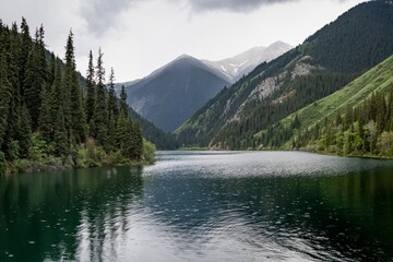 Kolsai high-altitude lake in the Tien Shan mountain system, Kazakhstan. Summer day, rainy weather. Travel, tourism, vacation, outdoor recreation.