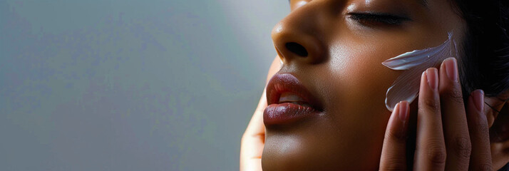 Close-up of woman applying cream on face..