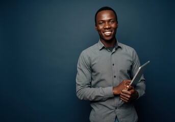 Wall Mural - Confident man holding tablet against dark background in casual attire