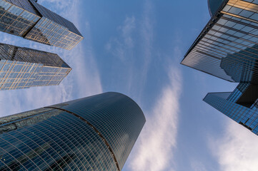 Angled view of modern skyscrapers in business district against blue sky. Looking Up high-rise office buildings.