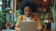 © Richa - Focused African American woman using laptop to manage business schedule, Generative AI