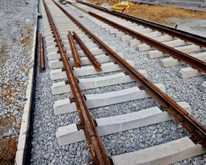 new and precise laying of tracks using leveling devices at the fork in two tram tracks. a layer of gravel above which concrete sleepers are placed. rubber anti-vibration base made of rubber