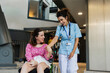 © Westend61 - Happy medical worker holding hand of woman sitting on wheelchair at hospital lobby