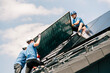 © Westend61 - Engineers wearing hardhats and installing solar panels on rooftop