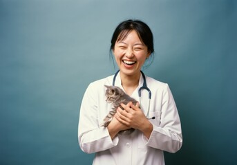 Smiling veterinarian holding a kitten against a blue background