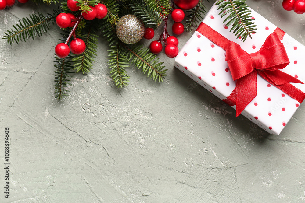 Christmas tree branches with rowan and gift box on grey background