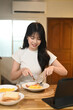© Prathankarnpap - Charming young woman in casual clothes enjoying breakfast in a modern kitchen