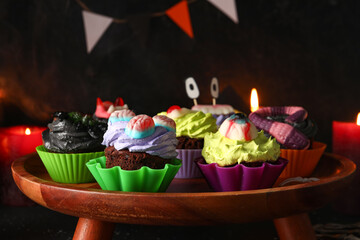 Wall Mural - Wooden stand with delicious Halloween cupcakes on dark background, closeup