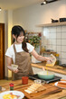 © Prathankarnpap - Young woman in apron pouring a beaten eggs from a glass bowl into a frying pan