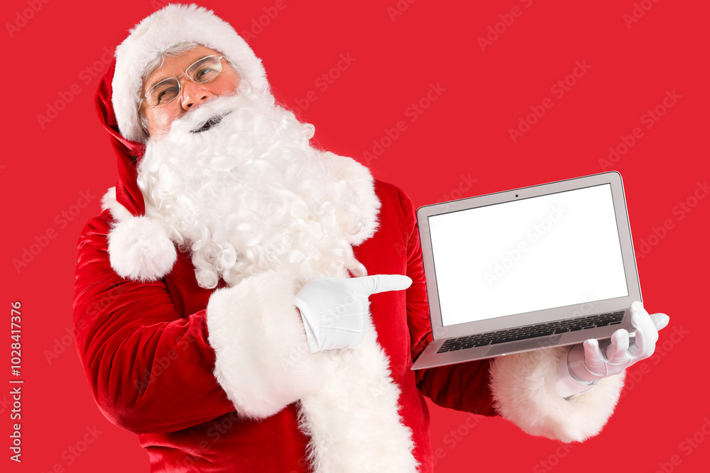 Santa Claus pointing at laptop on red background