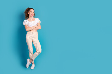 Wall Mural - Full size photo of pretty young girl look empty space crossed hands confident wear trendy white outfit isolated on blue color background