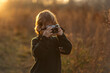 © Halfpoint - Portrait of cute girl taking photos with vintage camera in the middle of autumn meadow.