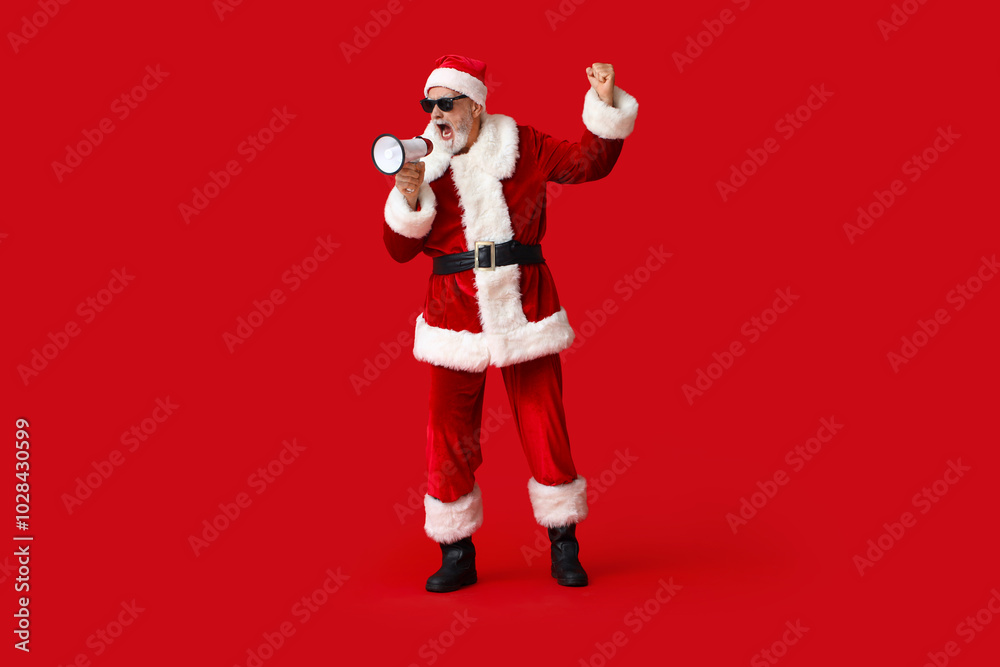 Santa Claus in sunglasses with megaphone screaming on red background