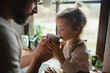 © Halfpoint - Father helping little daughter to drink warm tea from cup. Sick girl with cold is sitting on kitchen counter and drinking herbal tea.