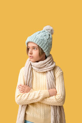 Wall Mural - Cute little boy in winter clothes on yellow background