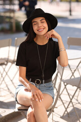 Poster - Beautiful young woman in stylish black hat on city street