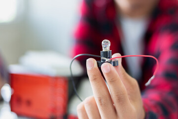 The study electrical circuit systems of students by experimenting with electrical connections using a small electric meter and a small flashlight bulb in physics science class, soft focus.