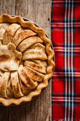 Poster - Apple pie with cinnamon on a wooden table with a red cloth, top view