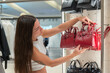 © ADDICTIVE STOCK - Young woman shopping for designer handbags in a store