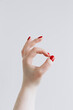 © ADDICTIVE STOCK - Female hand making okay gesture with red nails on white background