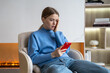© DimaBerlin - Upset woman received bad stressed news on phone, following ex-boyfriend on social media, sits with awful thoughts at home. Worried unhappy female using smartphone being cheated, hacked feels shock.
