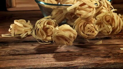 Wall Mural - Dry pasta falls on a wooden table. Filmed on a high-speed camera at 1000 fps. High quality FullHD footage