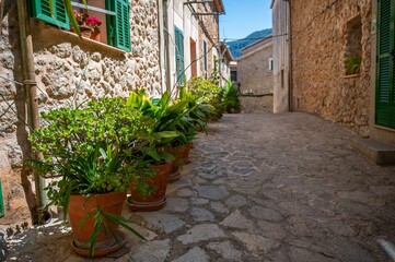 Charming narrow street in a village with stone houses under a clear blue sky in Valldemossa