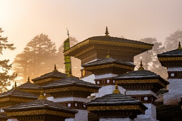 Sunrise through fog at the Dochula Pass Tibetan Buddhist Stupas Chorten in the Himalayas of Bhutan