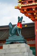 Fox statue with a red bib at Fushimi Inari Shrine in Kyoto, Japan.