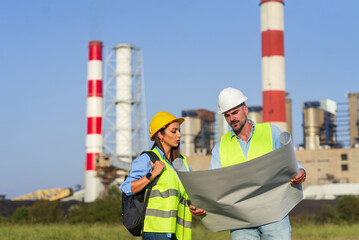 two engineers reviewing blueprints at industrial site