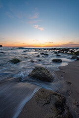 Wall Mural - water flowing around rocks on the beach shore.