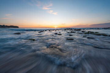 Wall Mural - beautiful sunrise over a rocky beach shore.