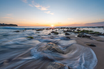 Wall Mural - beautiful sunrise over a rocky beach shore.
