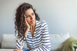© Dragana Gordic - Thoughtful Woman Sitting on Sofa in Striped Shirt at Home