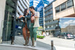 © Srdjan - Young happy couple in love waiting for their real estate agent to give them the tour of their new apartment to buy or for rent. Man and woman wait outside residential building of their new home.