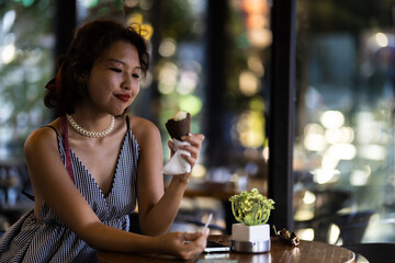 Wall Mural - Young woman enjoying an ice cream cone at a cozy cafe, feeling relaxed and content on a sunny day.