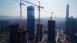 © Maksym - A wide shot of a construction site buzzing with activity, featuring several cranes working simultaneously to construct residential buildings, showcasing the scale of urban progress