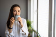 © Dragana Gordic - Woman Enjoying a Warm Cup of Coffee Near Window