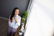 © Dragana Gordic - Woman Relaxing by Window with Coffee in Modern Room